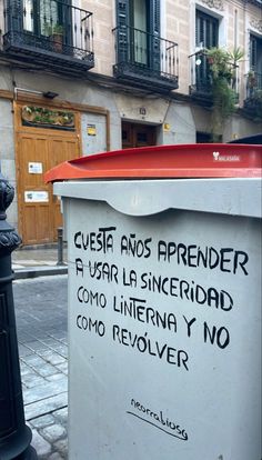 a trash can sitting on the side of a street