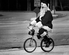 santa claus riding a bicycle down the street on his bike wearing a suit and hat