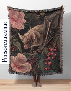 a bat is hanging on the side of a wall with flowers and leaves around it