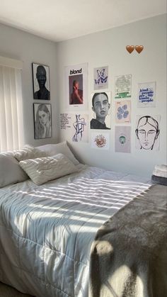 a bed sitting in a bedroom next to a window with pictures on the wall above it