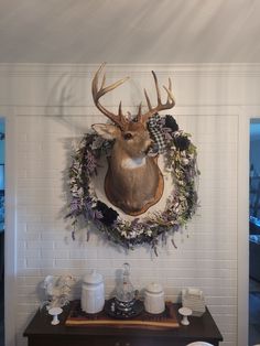 a deer head mounted on the wall above a table with plates and cups in front of it