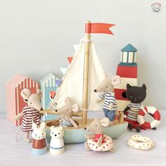 a group of toy mice sitting on top of a table next to a sailboat