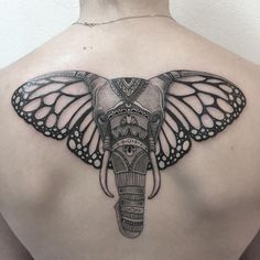 the back of a woman's upper body with an elephant and butterfly tattoo on it