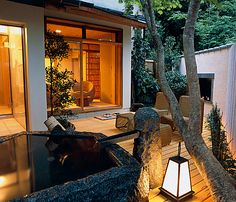 an outdoor living area with lights on the side and trees in the back yard at night