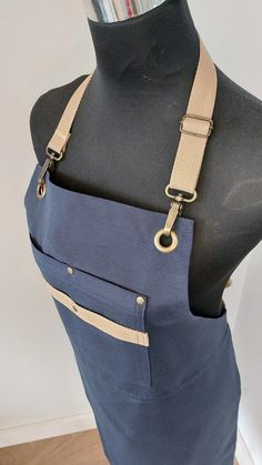 a mannequin wearing a blue apron with tan straps