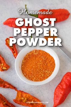 homemade ghost pepper powder in a white bowl surrounded by red chili peppers on a table