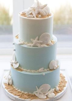 a three tiered cake decorated with seashells and sand