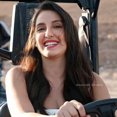 a woman is smiling while driving a tractor