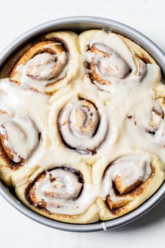 a pan filled with cinnamon rolls covered in icing