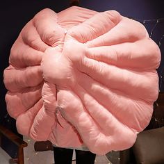 a large pink puffy pillow sitting on top of a person's back