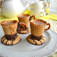 three ice cream cones are on a plate next to a teapot and saucer