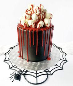 a chocolate cake with red and white icing on a silver plate next to a spider web