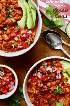 three bowls filled with chili, beans and avocado on top of a wooden table