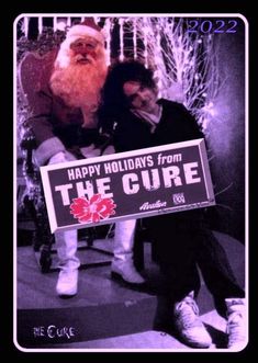 two people sitting next to each other in front of a sign that says happy holidays from the cure