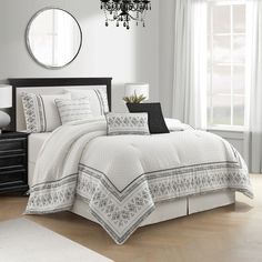 a white bed in a bedroom next to a window with a chandelier above it