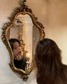 a woman standing in front of a mirror with her finger on her lips and looking at herself in the mirror