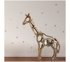 a gold giraffe sculpture sitting on top of a wooden floor next to a wall