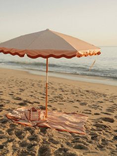 an umbrella and blanket on the beach near the ocean