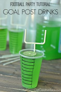 a green cup with a straw and lime on it sitting on a wooden table next to plastic cups