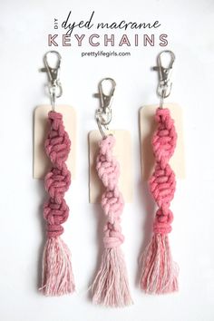 three pink and white key chains with tassels