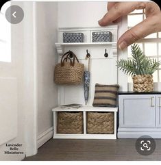 a white shelf with baskets and plants on it next to a hand reaching for the door