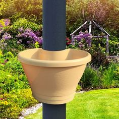 a planter hanging from the side of a pole in front of flowers and trees