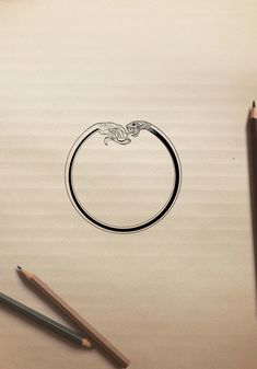 a drawing of a ring on top of a piece of paper with pencils next to it