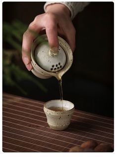 a person pours coffee into a small cup