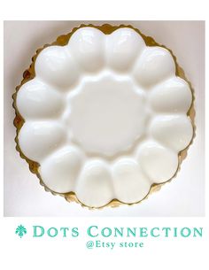 a white dish with gold trim on the edge and dots connection at the bottom, sitting on a table