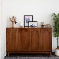 a wooden cabinet sitting next to a potted plant