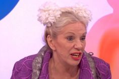 an older woman with white hair and flower in her hair is talking on the television show