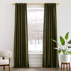 a green curtain hanging in front of a window next to a chair and potted plant