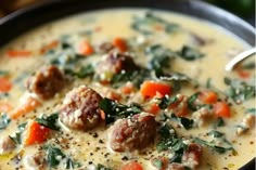 a bowl of soup with meatballs, carrots and spinach