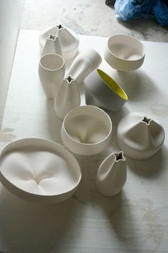 several white vases and bowls sitting on a table