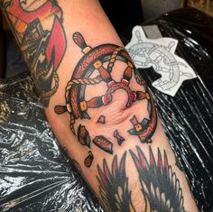 a man's arm with an anchor and ship wheel tattoo on it