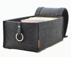 a black felt storage bin holds files and folders, with a leather ring at the bottom