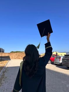 a woman holding up a graduation cap in the air