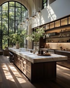 a kitchen with large windows and lots of counter space in front of the window are vases filled with flowers