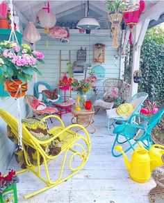 an outdoor covered porch with lots of chairs and flowers hanging from it's roof