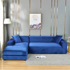 a blue couch sitting in front of a window next to a lamp on a wooden floor