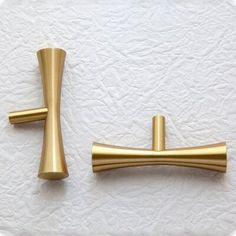 two brass colored handles on a white surface