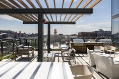 an outdoor dining area with tables and chairs overlooking the cityscape in the distance