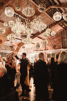 a group of people standing in a room with chandeliers hanging from the ceiling