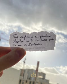 someone is holding up a piece of paper that has been written on it with the sky in the background