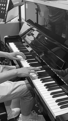 two people sitting at a piano playing music