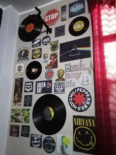 a wall covered in various records and stickers next to a red drapes curtain