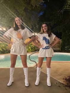 two women standing next to each other in front of a pool wearing white boots and t - shirts