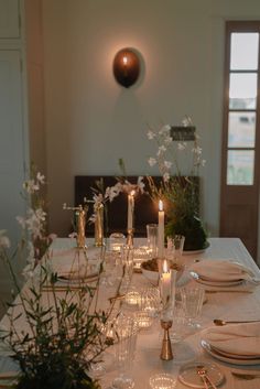 the table is set with candles, plates and silverware for an elegant dinner party