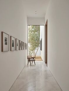 an empty hallway with pictures on the wall and a bench in front of one door