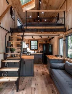 the interior of a tiny home with wood flooring and stairs leading up to the loft